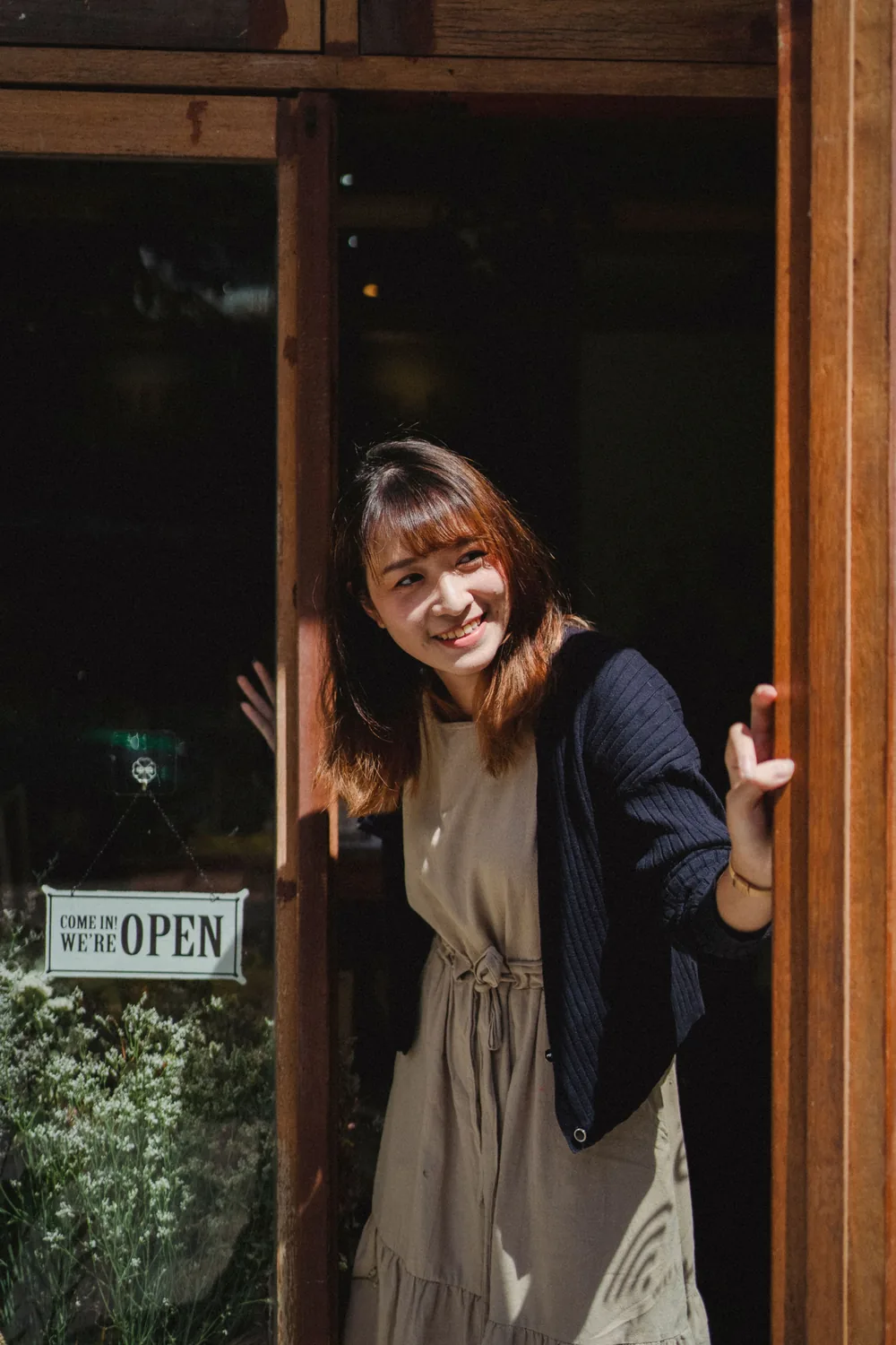 A smiling shop owner opening her front door